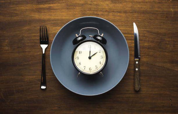 time to eat Alarm clock inside a plate fasting stock pictures, royalty-free photos & images