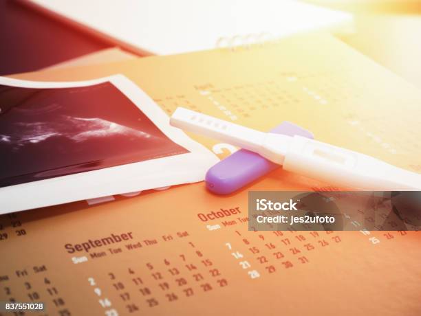 Pregnancy Test On Calendar With Ultrasound Background Stock Photo - Download Image Now