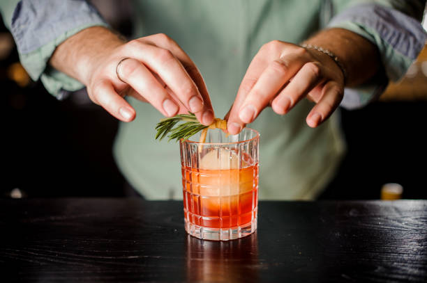 istock Bartender decorates cocktail with orange peel and rosemary 837555838
