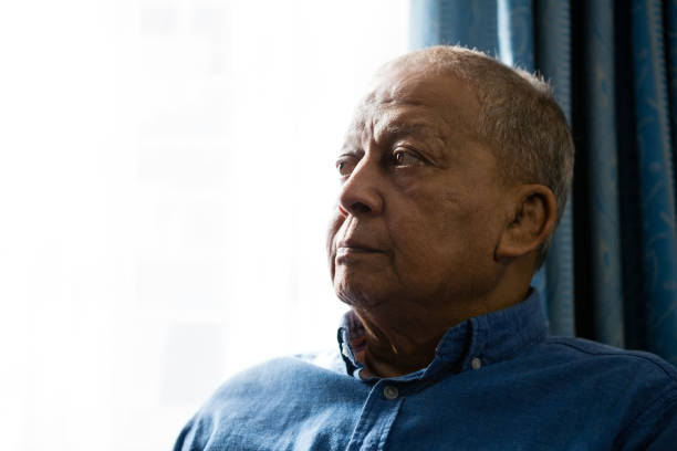istock Close up of senior man looking away while sitting by window 837557352