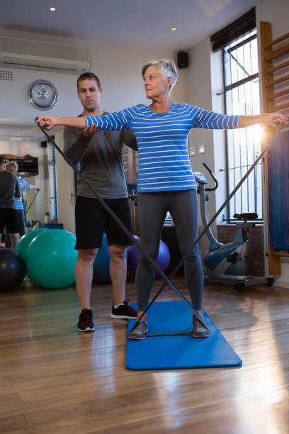 istock Male physiotherapist helping patient in performing exercise with resistance band 837559678