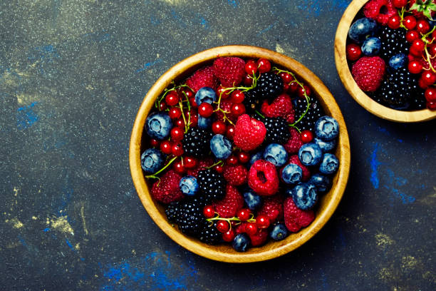 istock Colorful summer berries in assortment, black stone background, top view 837565148