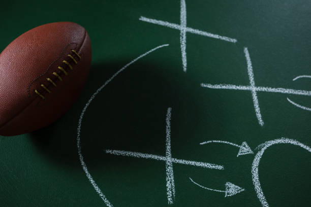 istock American football lying on green board with strategy drawn on it 837576086
