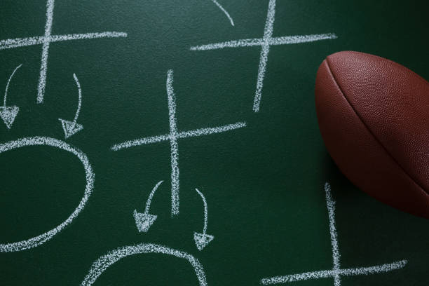 istock American football lying on green board with strategy drawn on it 837576144