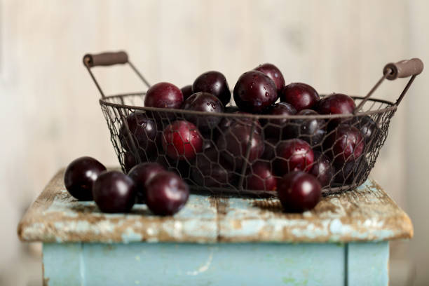 Ripe plums in a basket on a wooden background. Selective focus.