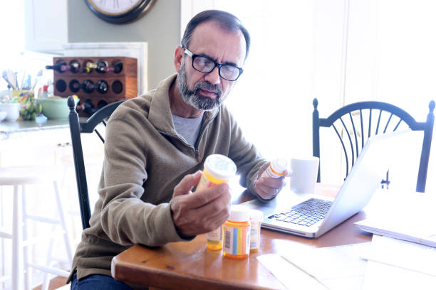 istock Hispanic Man Sitting At Dining Room Table Looking At His Prescription Medications 837647800