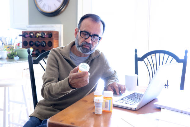 istock Hispanic Man Sitting At Dining Room Table Looking At His Prescription Medications 837648142