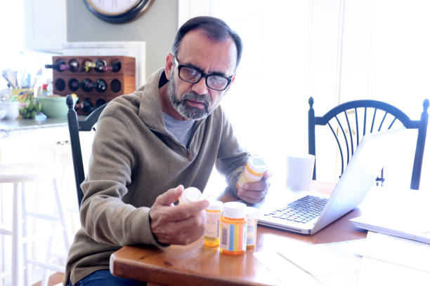 istock Hispanic Man Sitting At Dining Room Table Looking At His Prescription Medications 837648144