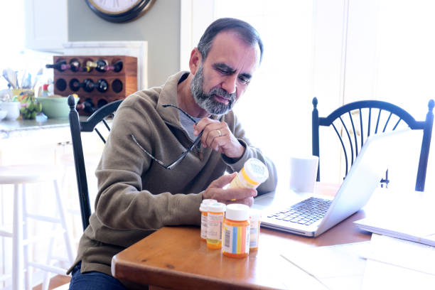 istock Hispanic Man Sitting At Dining Room Table Looking At His Prescription Medications 837648196