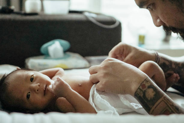 father changing baby boy (0-1 months) on bed - tattoo father family son imagens e fotografias de stock