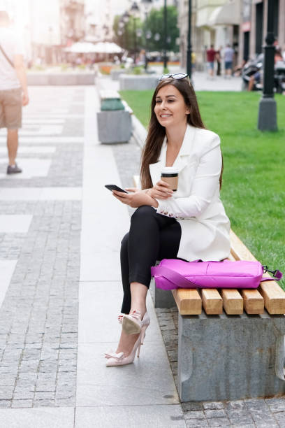 istock Businesswoman sitting on a bench and using a phone 837676496
