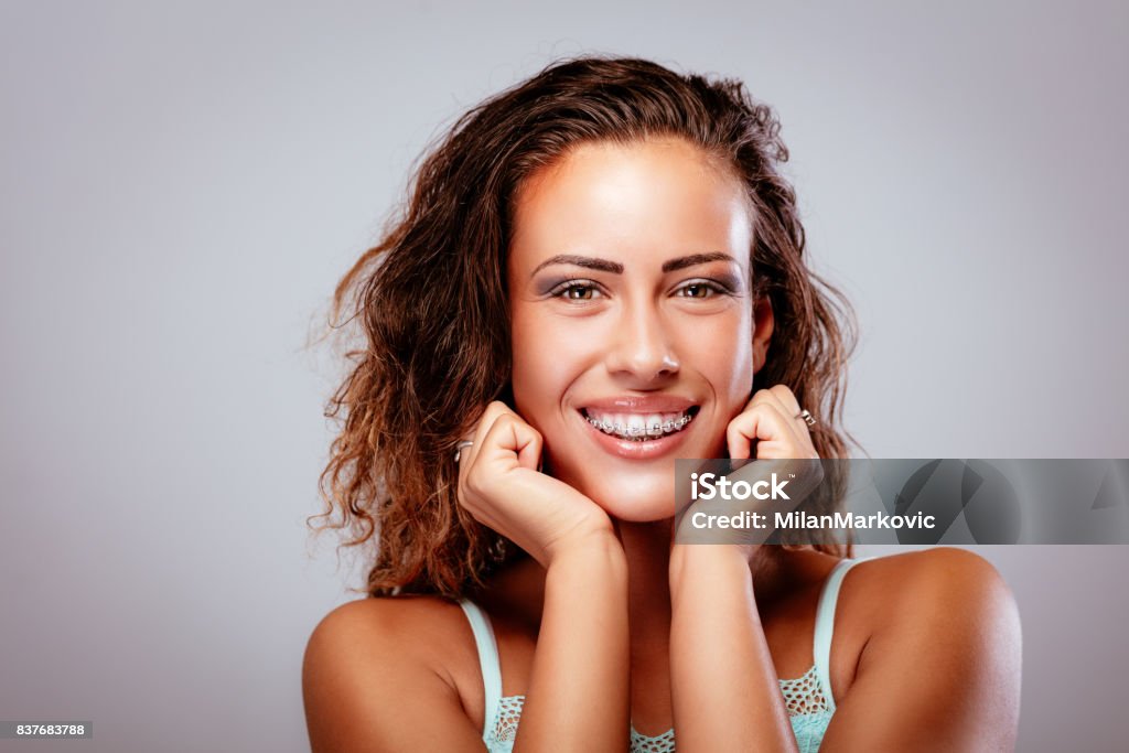 Girl With Braces Portait of a smiling young woman showing her perfect white teeth with braces. Looking at camera. Dental Braces Stock Photo