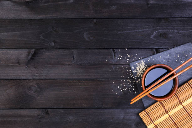 istock Background for sushi. Bamboo mat and soy sauce on black wooden table. Top view with copy space 837684364