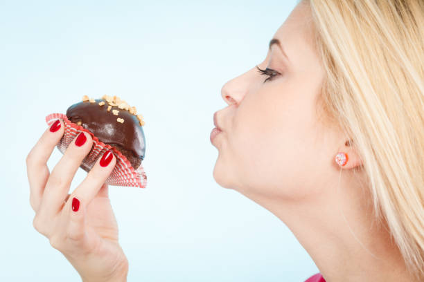 istock Woman holding chocolate cupcake about to bite 837745570