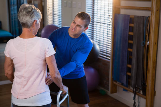 istock Physiotherapist assisting patient to walk with walking frame 837815908