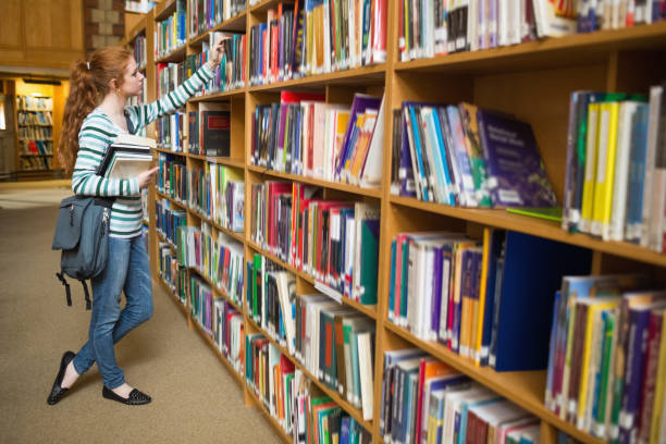 istock Redhead student taking book from shelf in the library 837836130