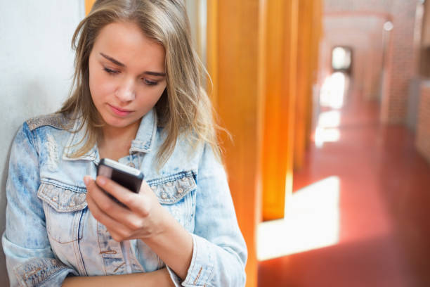 istock Pretty student standing in the hall sending a text 837871026