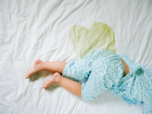 Bedwetting: Child pee on a mattress,Little girl feet and pee in bed sheet,Child development concept ,selected focus at wet on the bed stock photo