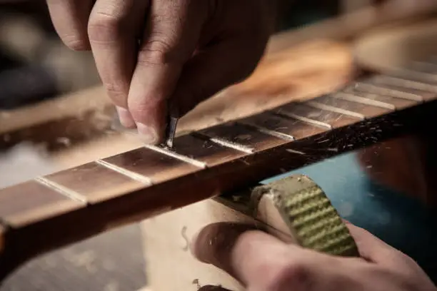 A close up in hands of a luthier fixing a guitar