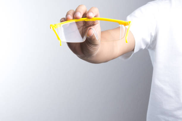 Hand holding safety glasses on white background