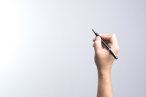 Hand holding a pen for signing or writing on white background