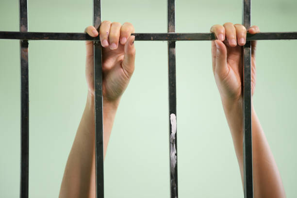 istock hands of prisoner in jail as background. 837926914