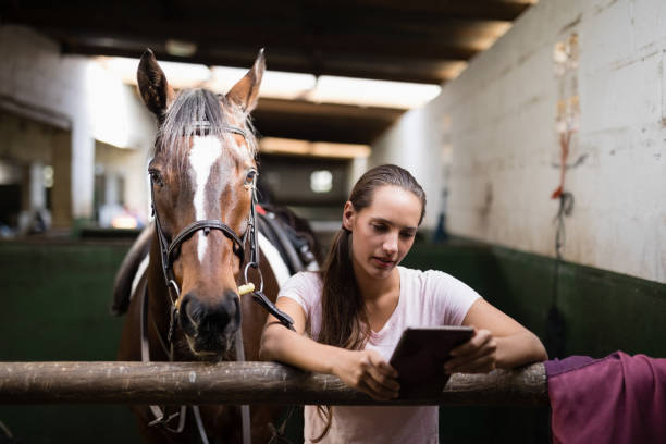 istock Female jockey using tablet computer while standing against horse 837946312