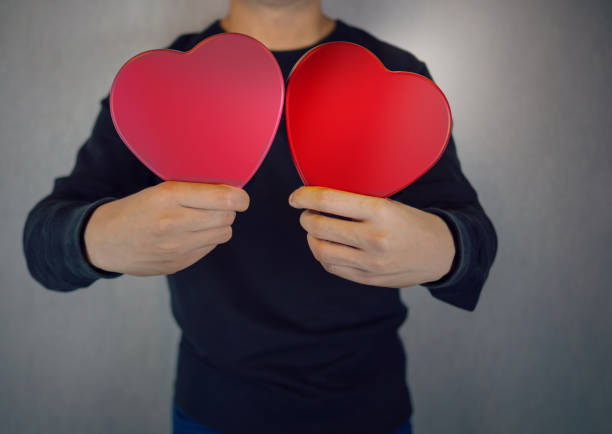 hearts in pink and red, holding by human - valentines day love nerd couple imagens e fotografias de stock