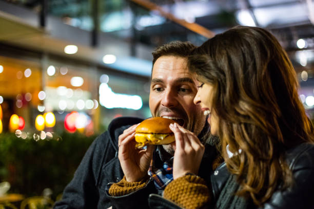 istock Couple sharing burger on city street 837997676
