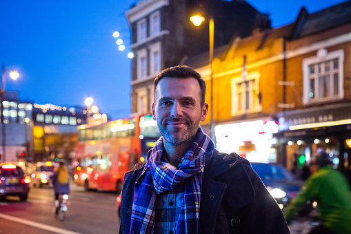 Portrait of handsome mature man on city street in evening. Man wearing winter wear looking at camera and smiling.