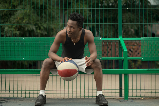 Portrait of african american man sitting on basketball court