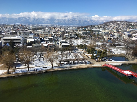 Matsumoto city covered by snow aerial view  with japanese alps mountains in background and blue sky in Nagano Japan