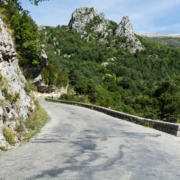 Mountain road between forests in Alpes-de-Haute-Provence department in southeastern France. Neighborhoods of a medieval city of Castellane and part of route Napoleon.
