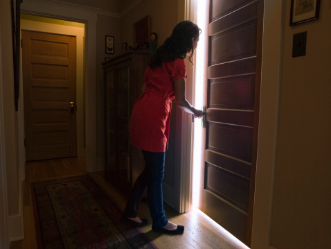 Woman opening bedroom door with light coming out