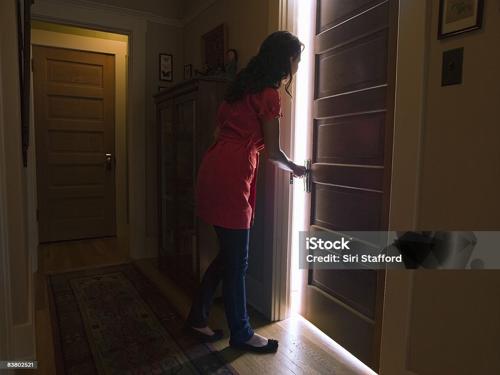 Woman opening bedroom door with light coming out Door Stock Photo