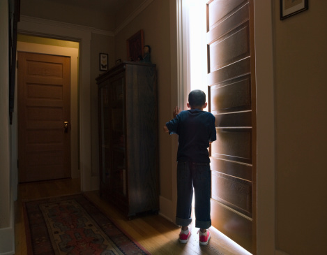 Boy peeking into room with light coming out