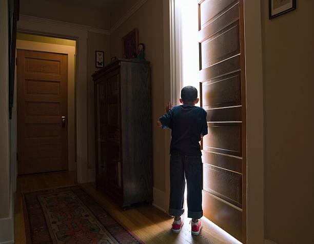 Boy peeking into room with light coming out Boy peeking into room with light coming out ajar stock pictures, royalty-free photos & images