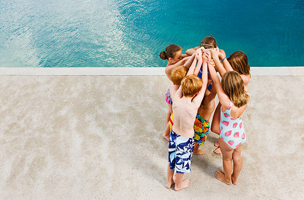 children linking arms above their heads by pool - 13427 뉴스 사진 이미지