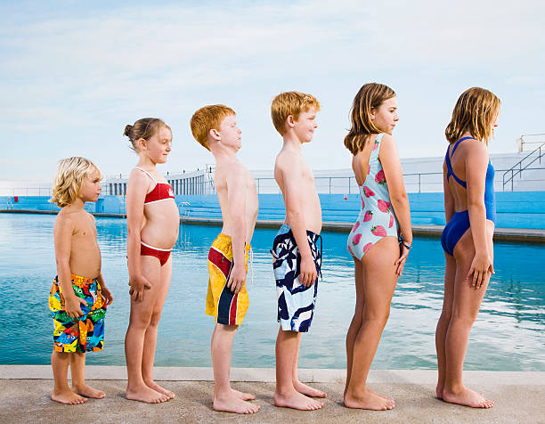 line of children standing to attention by pool - 13427 뉴스 사진 이미지