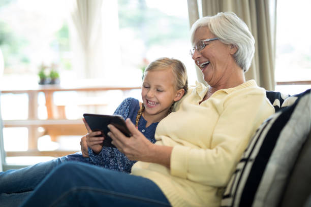 istock Smiling granddaughter and grandmother using digital tablet on sofa 838035948