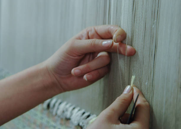 production and weaving of carpets and fabrics weaving and manufacturing of handmade carpets closeup. women's hands weave a carpet carpet factory stock pictures, royalty-free photos & images