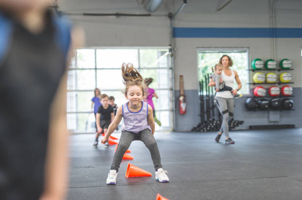 Never too young to start training A group of young children run through an obstacle course set up in the gym. They are all focused and having fun. A mom cheers them on. She is carrying a young child. chin ups photos stock pictures, royalty-free photos & images