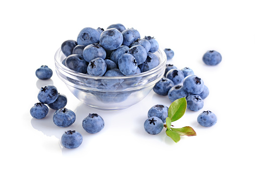 Above view of Over flowing white bowl of blueberries on blue background.