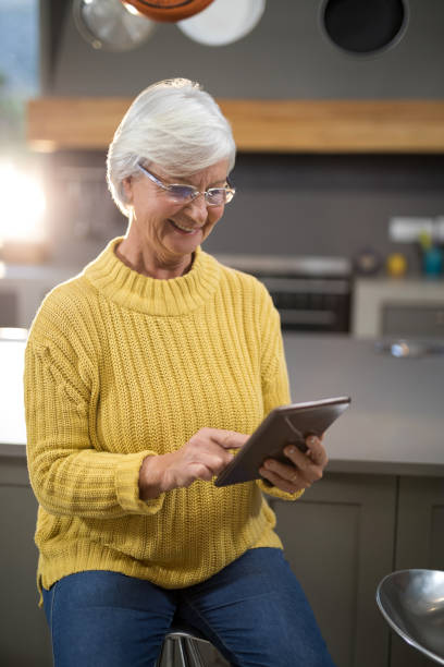 istock Smiling senior woman using digital tablet in kitchen 838055368