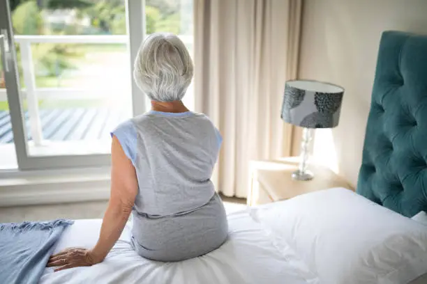 Photo of Senior woman sitting on bed in bedroom