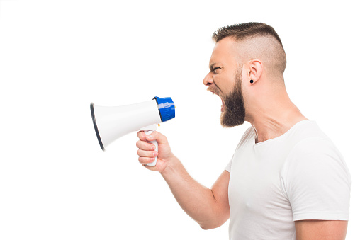'Portrait og young aggressive man using megaphone, isolated on white