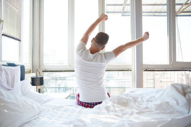 Man stretching in bed stock photo
