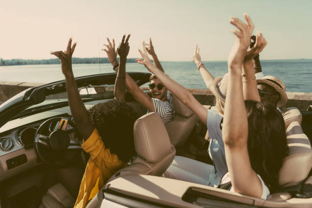 istock multicultural friends with outstretched arms riding car together at seaside 838075730