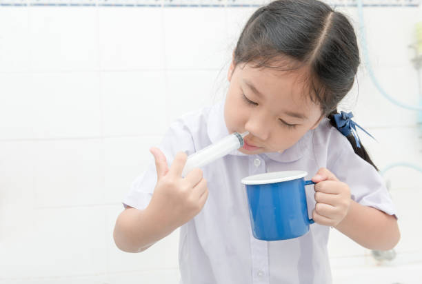 asiatische studentin spülung der nase mit spritze und kochsalzlösung - neti stock-fotos und bilder