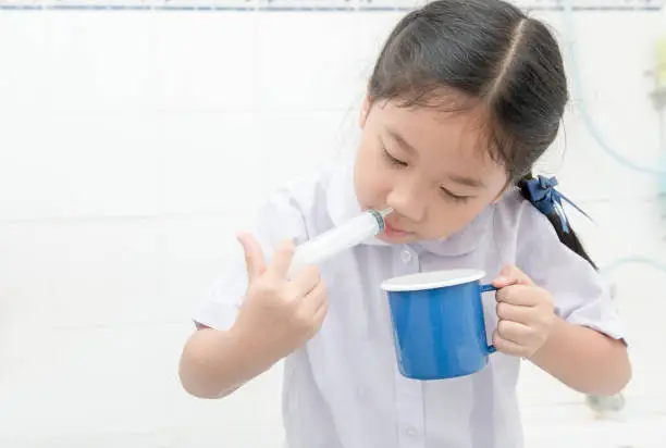 Nasal wash. asian student girl flushing her nose with syringe and saline in bathroom,Sinus Treatment and health care concept